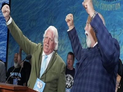 MUA Leader Paddy Crumlin and ILA President Harold Daggett with raised fists in the air on a stage